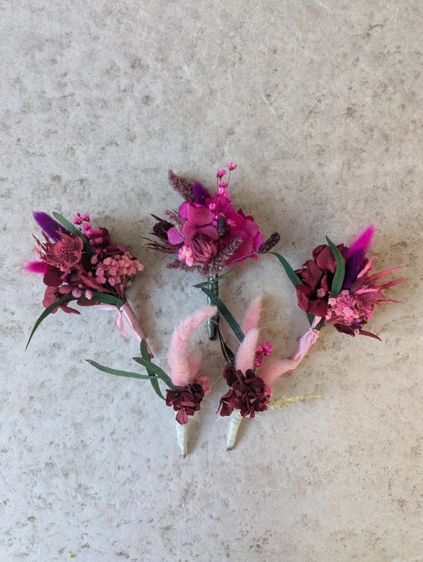 Buttonholes and charming country-style bouquets featuring pink pampas grass, hydrangea and foliage for a wedding.