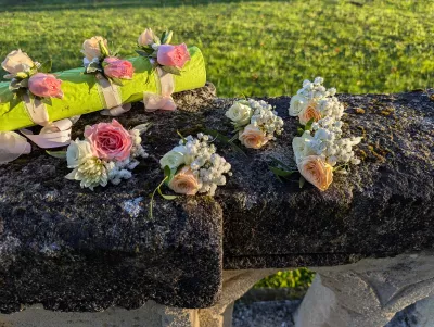Boutonnières et bracelets floraux bohèmes avec roses roses, chrysanthèmes blancs et gypsophile pour un mariage.