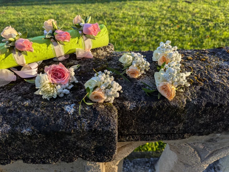 Bohemian buttonholes and floral bracelets featuring pink roses, white chrysanthemums and gypsophila for a wedding.