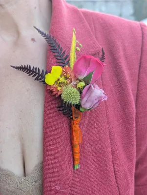 Boutonnière de mariage bohème, avec petite rose rose, fleur jaune, fougère et ruban orange pour le marié.