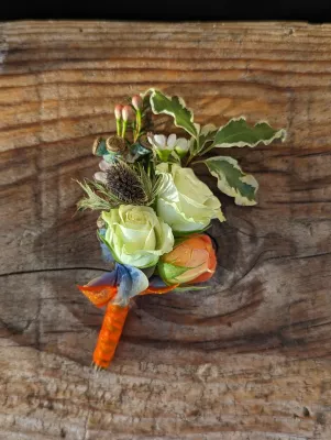 Boutonnière champêtre avec roses crème, orange et chardon, feuillage eucalyptus pour mariage Jennifer.