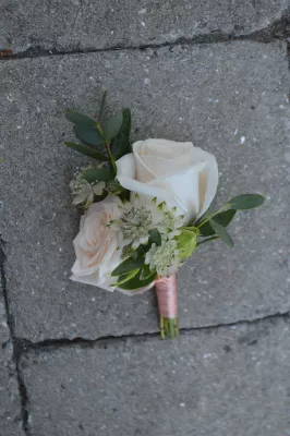 Boutonnière de mariage délicate avec une rose blanche, astrantia et eucalyptus, parfaite pour un style bohème.