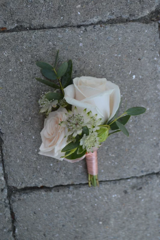 Delicate wedding buttonhole featuring a white rose, astrantia and eucalyptus, perfect for a bohemian style.