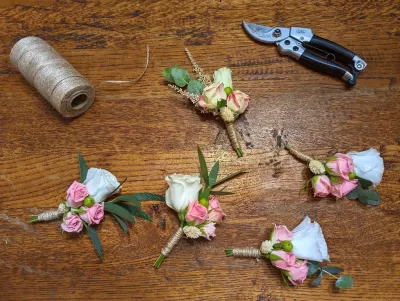 Rustic wedding buttonhole, featuring pink and white roses, eucalyptus leaves and dried elements, tied with natural twine.