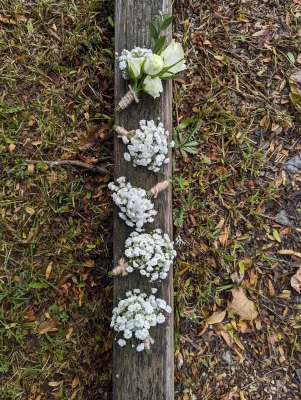 Boutonnière champêtre et élégante avec une rose blanche, de l'eucalyptus et du gypsophile pour un mariage d'été.