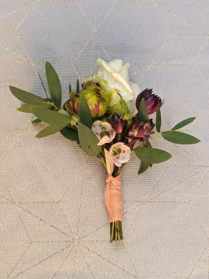 Boutonniere delicate pour mariage champetre, composee d'une rose blanche, petites fleurs pourpres et feuillage eucalyptus.