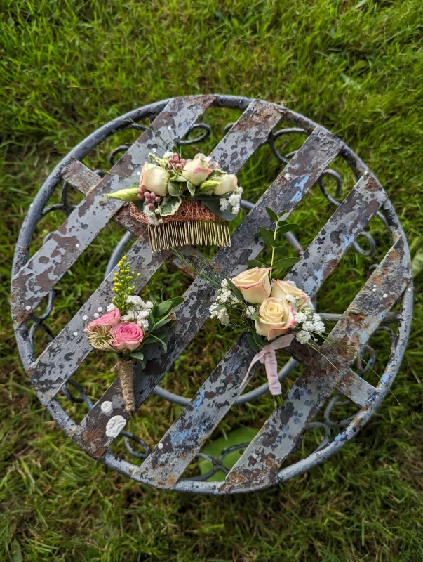 Boutonnière délicate style champêtre avec roses crème, gypsophile et feuillage eucalyptus, parfaite pour un mariage d'été.