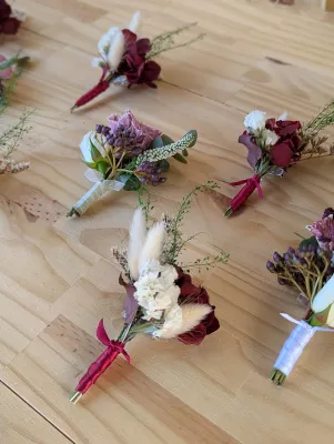 Boutonnière de mariage style bohème avec rose bordeaux, fleurs séchées crème et feuillage pour le mariage Océane à Tabanac.