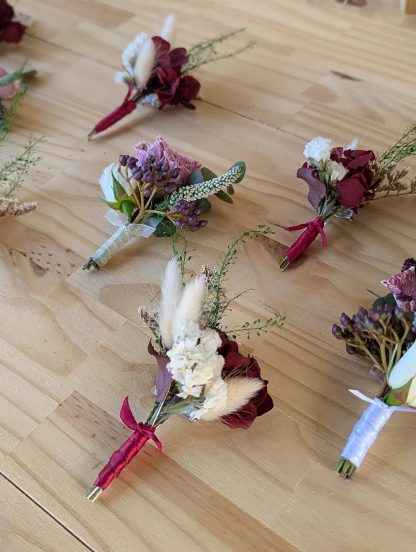 Boutonnière de mariage style bohème avec rose bordeaux, fleurs séchées crème et feuillage pour le mariage Océane à Tabanac.