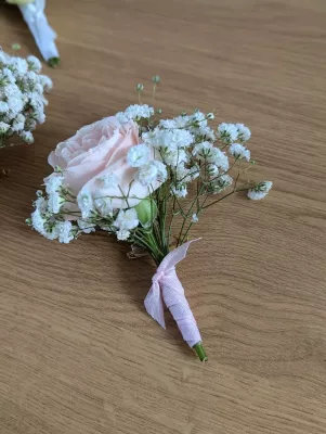 Boutonnière de mariage classique avec une rose rose pâle et du gypsophile, idéale pour le marié ou les témoins.