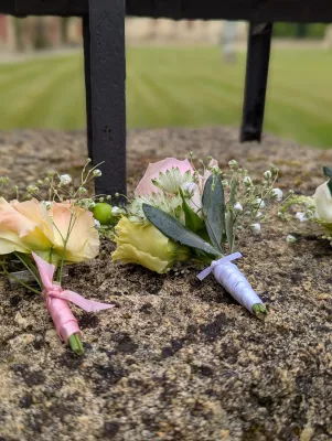 Boutonnières champêtres sophistiquées avec roses pâles, lisianthus et eucalyptus pour mariage.
