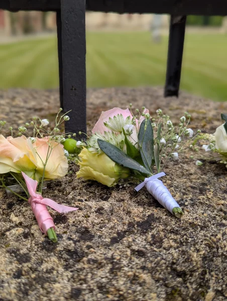Boutonnières champêtres sophistiquées avec roses pâles, lisianthus et eucalyptus pour mariage.