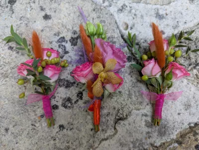 Buttonholes with pink roses, yellow orchids and foliage, organic romantic style.