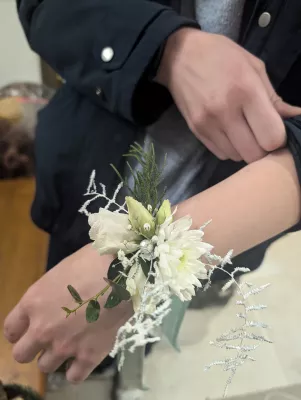 Bracelet floral classique avec chrysanthème et lisianthus blancs, feuillage givré, pour un mariage d'hiver élégant.