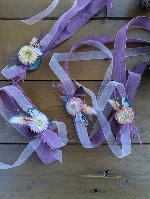 Sophisticated rustic floral bracelets with pink immortelles and lagurus on purple ribbons.