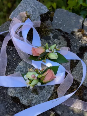Bracelets floraux romantiques organiques avec roses roses, freesias blancs et feuillage vert, rubans.