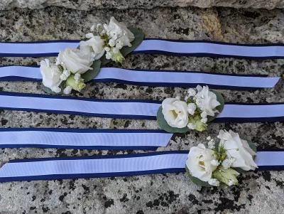 Bracelet floral champêtre pour mariage de Sandra, avec roses blanches, gypsophile et ruban bleu à Saint-Vincent-de-Pertignas.