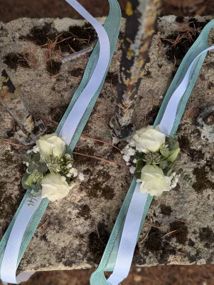 Two sophisticated country-style floral bracelets with cream roses and gypsophila for a wedding.