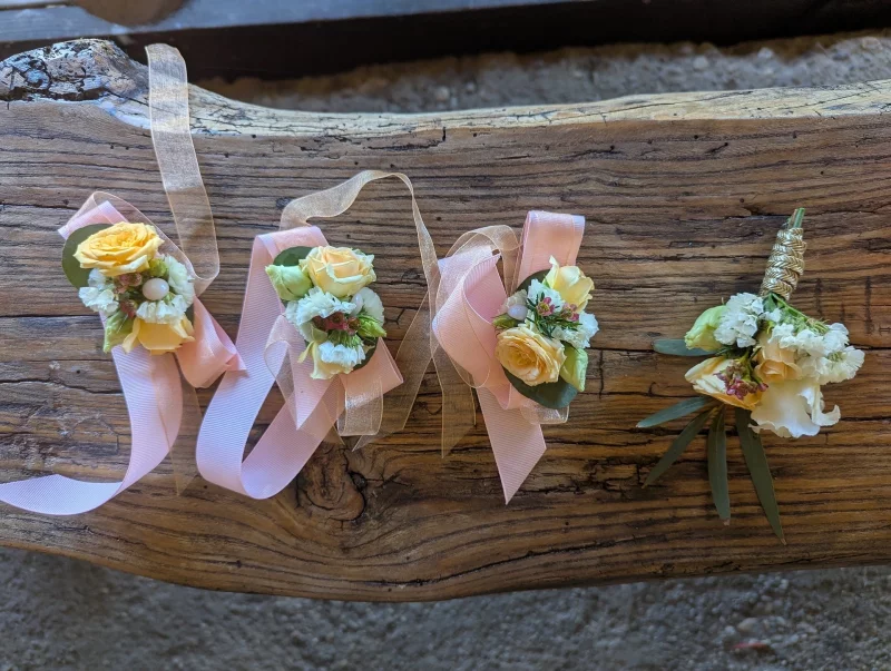 Bracelet floral de mariage classique, avec des roses jaunes pâles, des petites fleurs blanches et du feuillage vert sauge.