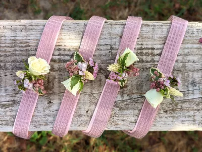 Bracelets floraux champêtres avec roses blanches, feuillage panaché et petites fleurs roses pour le mariage.