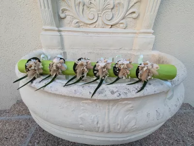 Bracelets floraux bohèmes avec fleurs séchées, pampas et feuillage vert, présentés sur un support vert clair.