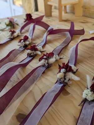 Bracelet floral de mariage bohème avec rose bordeaux, fleurs séchées et ruban bordeaux, élégant accessoire pour un mariage.