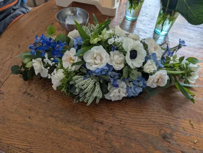 Centre de table floral classique pour mariage hivernal. Composition élégante avec anémones, roses blanches et delphiniums bleus.