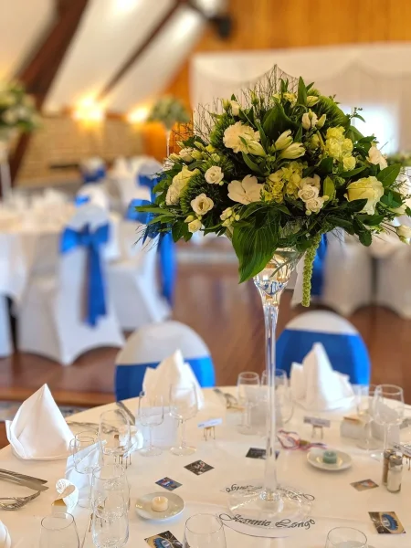 Centre de table classique et moderne sur vase haut pour mariage, avec lisianthus, roses blanches et feuillage vert.