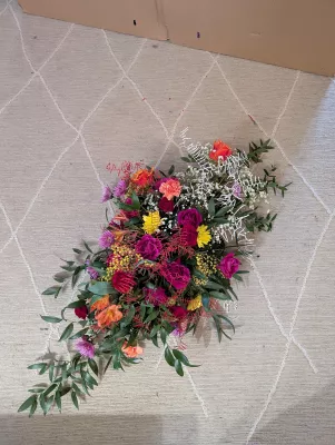 Vibrant and exotic floral arrangement with roses, mimosa, alstroemeria and carnations for a bold table centrepiece.