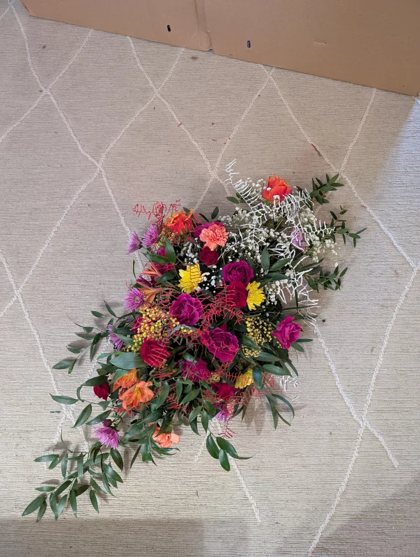 Vibrant and exotic floral arrangement with roses, mimosa, alstroemeria and carnations for a bold table centrepiece.