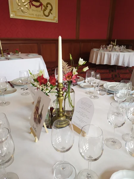 Gros plan sur un centre de table classique avec alstroemerias, stocks roses et feuillage, agrémenté d'une bougie.