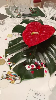Exotic wedding table centrepiece, featuring a vibrant red anthurium bloom and a large green monstera leaf, perfect for a spring wedding.