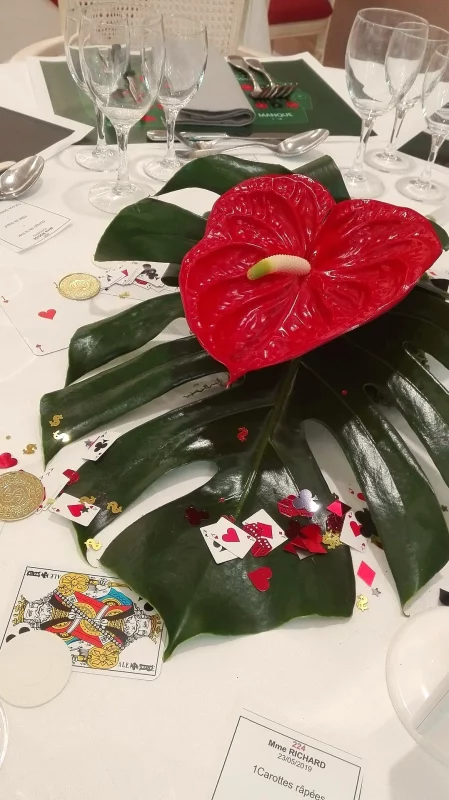 Exotic wedding table centrepiece, featuring a vibrant red anthurium bloom and a large green monstera leaf, perfect for a spring wedding.