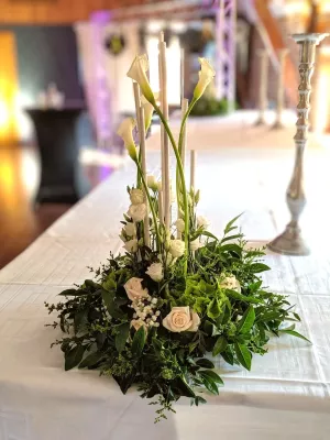 Grand centre de table de mariage classique, avec des arums élégants, roses et feuillage luxuriant, rehaussé de bougies hautes.