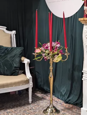 Chandelier doré élégant avec chandelles rouges et petite composition d'orchidées et anthuriums, style classique.