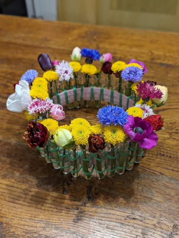 A vibrant rustic table centrepiece with yellow chrysanthemums, blue cornflowers and tulips for a spring wedding.