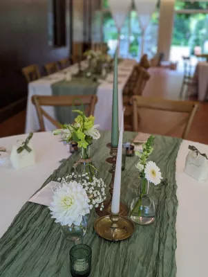 Composition de centre de table champêtre avec dahlia blanc, gypsophile, et antirrhinum verts pour un mariage.
