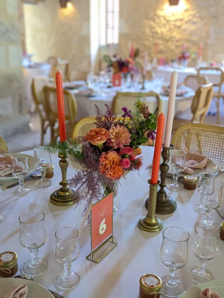 Centre de table avec dahlias roses, roses orange, pampa rose et bougies corail, style champêtre sophistiqué.