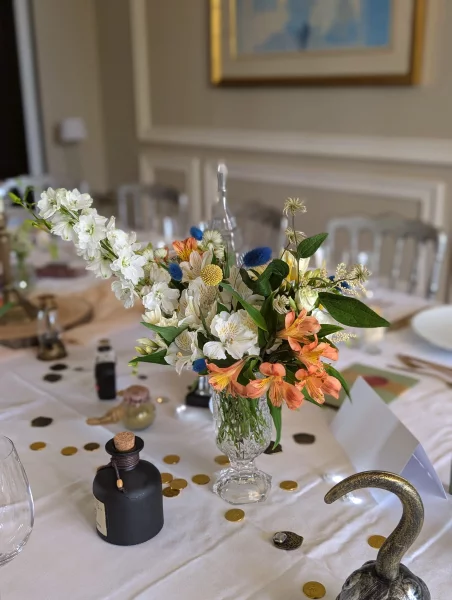 Sophisticated rustic table centrepiece with white delphinium, orange alstroemeria and blue thistle for a wedding.