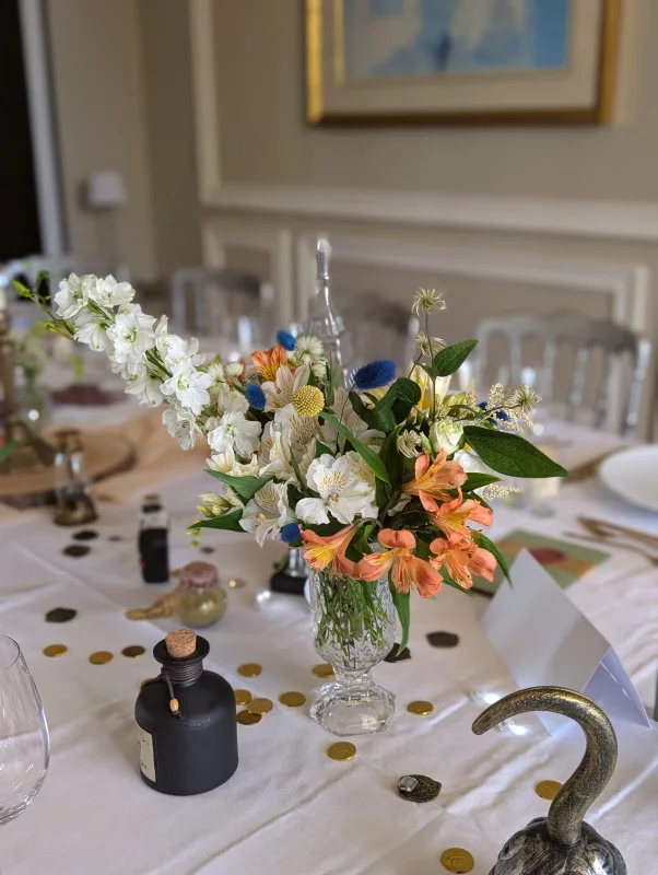 Sophisticated rustic table centrepiece with white delphinium, orange alstroemeria and blue thistle for a wedding.