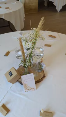 Élégant centre de table de mariage bohème avec delphinium, roses, pampa et bougies flottantes.