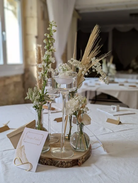 Élégant centre de table de mariage bohème avec delphinium, roses, pampa et bougies flottantes.