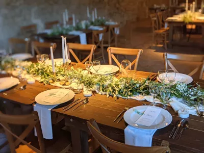 Détail d'un centre de table champêtre avec guirlande de feuillage vert et petites fleurs blanches.