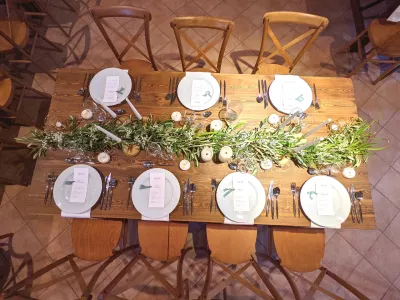 Centre de table champêtre pour mariage, composé d'une guirlande de feuillage verdoyant et de délicates fleurs blanches.