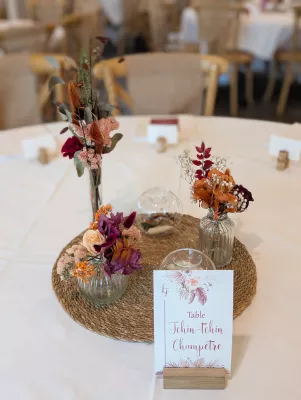 Rustic table centrepiece with dried orange, terracotta and burgundy flowers and a cream rose.