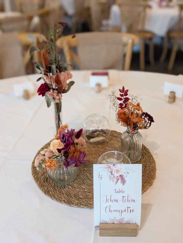 Rustic table centrepiece with dried orange, terracotta and burgundy flowers and a cream rose.
