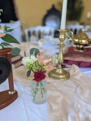 Sophisticated rustic table centrepiece with white freesia, pink-orange gloriosa and red rose for a wedding.