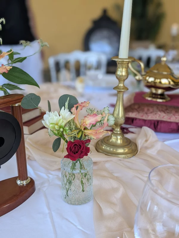 Sophisticated rustic table centrepiece with white freesia, pink-orange gloriosa and red rose for a wedding.