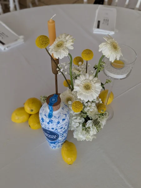 Centre de table de mariage champêtre moderne avec gerberas blancs, craspedias jaunes et citrons frais