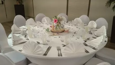 Centre de table de mariage champêtre avec un gérbera rose, des marguerites et des petites roses dans un pot en verre sur un rondin de bois.